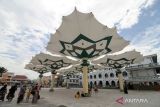 Warga berfoto dengan latar belakang payung madinah di depan Masjid Agung Al-Anwar di kawasan Alun-alun Kota Pasuruan, Jawa Timur, Sabtu (11/2/2023). Kunjungan wisatawan Kota Pasuruan mengalami kenaikan setelah pembangunan payung madinah dan revitalisasi kawasan alun-alun yang menghabiskan anggaran Rp 17 miliar. ANTARA Jatim/Umarul Faruq/zk 