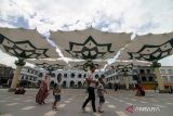 Pengunjung melintas di wiisata payung madinah di depan Masjid Agung Al-Anwar di kawasan Alun-alun Kota Pasuruan, Jawa Timur, Sabtu (11/2/2023). Kunjungan wisatawan Kota Pasuruan mengalami kenaikan setelah pembangunan payung madinah dan revitalisasi kawasan alun-alun yang menghabiskan anggaran Rp 17 miliar. ANTARA Jatim/Umarul Faruq/zk 