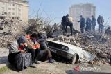 Warga duduk di dekat reruntuhan bangunan terdampak gempa di Kahramanmaras, Turki, Selasa (14/2/2023). ANTARA FOTO/REUTERS/Nir Elias/rwa