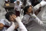 Petugas kesehatan memberikan tetesan vaksin polio (Oral Poliomyelitis Vaccine) tahap dua kepada pelajar di Sekolah Dasar Negeri 3, Lhokseumawe, Aceh, Rabu (15/2/2023). Dinas Kesehatan Aceh mencatat sudah lebih dari 615 ribu anak atau 50.5 persen dari total sasaran sekitar 1.217.939 anak usia 0-12 tahun yang ditarget mendapatkan imunisasi polio dosis kedua selama pelaksanaan Sub Pekan Imunisasi Nasional (PIN) polio di Aceh. Antara Aceh/Rahmad.
