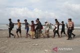 Pesonil Polri  dan TNI mengawal  imigran etnis Rohingya menuju mobil angkutan untuk dipindahkan ke lokasi penampungan sementara usai terdampar di Desa Lampanah Leugah, Kecamatan Seulimeuem, Aceh Besar, Aceh, Kamis (16/2/2023). Sebanyak 62 orang imigran etnis Rohingya terdiri dari 23 orang laki-laki dewasa , 21 orang perempuan dewasa  dan 18 orang anak-anak menaiki perahu  terdampar di pantai Desa Lampanah Leugah, kabupaten Aceh Besar. ANTARA FOTO/Ampelsa.