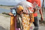 Pesonil Polri  dan TNI mengawal  imigran etnis Rohingya menuju mobil angkutan untuk dipindahkan ke lokasi penampungan sementara usai terdampar di Desa Lampanah Leugah, Kecamatan Seulimeuem, Aceh Besar, Aceh, Kamis (16/2/2023). Sebanyak 62 orang imigran etnis Rohingya terdiri dari 23 orang laki-laki dewasa , 21 orang perempuan dewasa  dan 18 orang anak-anak menaiki perahu  terdampar di pantai Desa Lampanah Leugah, kabupaten Aceh Besar. ANTARA FOTO/Ampelsa.