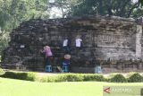 Pekerja membersihkan lumut yang tumbuh pada relief candi Tegowangi menggunakan lidi di Desa Tegowangi, Kediri, Jawa Timur, Selasa (21/2/2023). Candi Hindu yang dibangun pada masa Kerajaan Majapahit sekitar tahun 1400 masehi tersebut saat musim hujan dilakukan pembersihan lumut secara berkelanjutan guna mencegah keroposnya relief. ANTARA Jatim/Prasetia Fauzani/zk