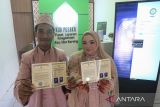 Sepasang pengantin memperlihatkan buku nikah usai melaksanakan akad nikah di Kantor Urusan Agama (KUA) Ulee Kareng, Banda Aceh, Aceh, Kamis (23/2/2023). Antara Aceh/Khalis Surry