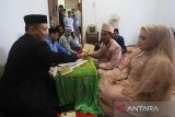 Penghulu Harun Usman (kiri) menyerahkan buku nikah kepada pengantin usai melaksanakan akad nikah di Kantor Urusan Agama (KUA) Ulee Kareng, Banda Aceh, Aceh, Kamis (23/2/2023). Antara Aceh/Khalis Surry