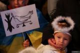 Seorang anak yang berpakaian seperti malaikat berdiri di dekat anak lain yang dibungkus dengan bendera Ukraina, saat pertemuan untuk menandai peringatan satu tahun invasi Rusia ke Ukraina, di pusat kota Madrid, Spanyol, Jumat (24/2/2023). ANTARA FOTO/Reuters- Februari 2023. Reuters//Violeta Santos Moura/hp.
