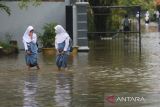 Siswa terpaksa dipulangkan lebih awal akibat sekolah mereka terendam banjir di Indramayu, Jawa Barat, Senin (27/2/2023). Banjir yang merendam sejumlah kawasan tersebut akibat hujan deras yang mengguyur sejak tiga hari terakhir. ANTARA FOTO/Dedhez Anggara/agr