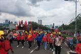 Massa kelompok buruh berjalan kaki menuju depan gedung DPR RI