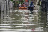 Warga menggunakan perahu karet melintasi genangan banjir di kawasan Karangligar, Kabupaten Karawang, Jawa Barat, Rabu (1/3/2023). Ratusan rumah warga dari 55 desa yang tersebar di 18 kecamatan masih terendam banjir akibat luapan Sungai Cibeet dan Sungai Citarum. ANTARA FOTO/Novrian Arbi/agr