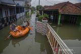 Warga menggunakan perahu karet melintasi genangan banjir di kawasan Karangligar, Kabupaten Karawang, Jawa Barat, Rabu (1/3/2023). Ratusan rumah warga dari 55 desa yang tersebar di 18 kecamatan masih terendam banjir akibat luapan Sungai Cibeet dan Sungai Citarum. ANTARA FOTO/Novrian Arbi/agr