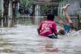 Warga berjalan melintasi genangan banjir di kawasan Karangligar, Kabupaten Karawang, Jawa Barat, Rabu (1/3/2023). Ratusan rumah warga dari 55 desa yang tersebar di 18 kecamatan masih terendam banjir akibat luapan Sungai Cibeet dan Sungai Citarum. ANTARA FOTO/Novrian Arbi/agr