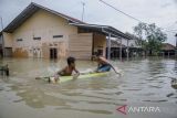 Anak-anak bermain di genangan banjir di kawasan Karangligar, Kabupaten Karawang, Jawa Barat, Rabu (1/3/2023). Ratusan rumah warga dari 55 desa yang tersebar di 18 kecamatan masih terendam banjir akibat luapan Sungai Cibeet dan Sungai Citarum. ANTARA FOTO/Novrian Arbi/agr