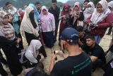 Pegiat dari Komunitas Konservasi Penyu Lampuuk menggunakan bola pimpong sebagai pengganti telur penyu saat menjelaskan cara relokasi dan penetasan telur penyu secara semi alamiah kepada wisatawan di Pantai Lampuuk, Aceh Besar, Aceh, Jumat (3/3/2023). Antara Aceh/Khalis Surry