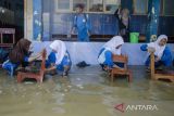 Murid membersihkan kursi kelas pada genangan banjir di SMPN 1 Telukjambe Barat, Karangligar, Kabupaten Karawang, Jawa Barat, Jumat (3/3/2023). Sekolah tersebut menjadi salah satu fasilitas pendidikan yang terendam setinggi 30 cm hingga 1,5 meter akibat banjir yang melanda sejak senin (27/2) sehingga mengganggu jalannya aktivitas pedidikan. ANTARA FOTO/Novrian Arbi/agr
