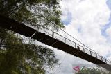 Warga  melintasi jembatan gantung yang menghubungkan beberapa perkampungan di pedalaman desa Guba, Kecamatan Seulimum, kabupaten Aceh Besar, Aceh, Sabtu (4/3/2023. Jembatan gantung yang memiliki panjang sekitar 200 meter itu mengalami kerusakan pada bagian lantai papannya karena sudah lapuk sehingga dapat mengancam keselamatan warga. ANTARA FOTO/Ampelsa.