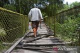 Warga  melintasi jembatan gantung yang menghubungkan beberapa perkampungan di pedalaman desa Guba, Kecamatan Seulimum, kabupaten Aceh Besar, Aceh, Sabtu (4/3/2023. Jembatan gantung yang memiliki panjang sekitar 200 meter itu mengalami kerusakan pada bagian lantai papannya karena sudah lapuk sehingga dapat mengancam keselamatan warga. ANTARA FOTO/Ampelsa.