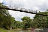 Warga  melintasi jembatan gantung yang menghubungkan beberapa perkampungan di pedalaman desa Guba, Kecamatan Seulimum, kabupaten Aceh Besar, Aceh, Sabtu (4/3/2023. Jembatan gantung yang memiliki panjang sekitar 200 meter itu mengalami kerusakan pada bagian lantai papannya karena sudah lapuk sehingga dapat mengancam keselamatan warga. ANTARA FOTO/Ampelsa.