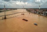 Foto udara kapal tongkang bermuatan batu bara melintasi Sungai Batanghari di Kasang, Jambi, Rabu (8/3/2023). Data Dinas Perhubungan Provinsi Jambi menyebutkan dari puluhan perusahaan pemegang Izin Usaha Pertambangan (IUP) di daerah itu, baru dua perusahaan yang memanfaatkan jalur sungai untuk angkutan batu bara, sedangkan sisanya masih melalui jalur darat karena ada kendala pendangkalan di beberapa titik di sungai. ANTARA FOTO/Wahdi Septiawan/nym.