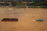 Foto udara kapal tongkang bermuatan batu bara melintasi Sungai Batanghari di Kasang, Jambi, Rabu (8/3/2023). Data Dinas Perhubungan Provinsi Jambi menyebutkan dari puluhan perusahaan pemegang Izin Usaha Pertambangan (IUP) di daerah itu, baru dua perusahaan yang memanfaatkan jalur sungai untuk angkutan batu bara, sedangkan sisanya masih melalui jalur darat karena ada kendala pendangkalan di beberapa titik di sungai. ANTARA FOTO/Wahdi Septiawan/nym.