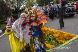 Warga berfoto dengan peserta saat Fashion Carnaval Sasirangan dan Pawai Basasirangan di Kawasan Siring Sungai Martapura, Banjarmasin, Kalimantan Selatan, Sabtu (11/3/2023). Kegiatan yang diikuti 30 peserta karnaval dan 2.845 peserta pawai dalam rangkaian Banjarmasin Sasirangan Festival (BSF) 2023 itu sebagai upaya mendorong pengrajin kain sasirangan agar lebih maju, kreatif dan berdaya secara ekonomi. ANTARA/Bayu Pratama S.