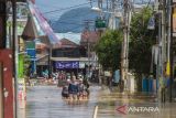 Sejumlah warga melintasi jalan yang tergenang banjir di Barabai, Kabupaten Hulu Sungai Tengah, Kalimantan Selatan, Jumat (17/3/2023). Berdasarkan data BPBD Kabupaten Hulu Sungai Tengah pada Jumat (17/3/2023) sebanyak 4.188 jiwa dan 1.340 rumah di lima kecamatan terdampak banjir di kabupaten tersebut. ANTARA/Bayu Pratama S.