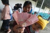 Warga penerima manfaat memperlihatkan uang saat pencairan Bantuan Pangan Non Tunai (BPNT) dan Program Keluarga Harapan (PKH) di Kantor Pos Besar, Kota Kediri, Jawa Timur, Kamis (30/3/2023). Pemeritah Kota Kediri menyalurkan BPNT kepada 2.269 kelurga penerima manfaat dan PKH kepada 795 keluarga penerima manfaat sebagai upaya mengentaskan kemiskinan. ANTARA Jatim/Prasetia Fauzani/zk