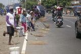 Sejumlah warga menunggu pengendara memberi sedekah dengan melempar uang di Jembatan Sewo, Jalur Pantura Sukra Indramayu, Jawa Barat, Senin (17/4/2023). Aksi mengambil uang sedekah menggunakan sapu tersebut dapat membahayakan keselamatan pengguna jalan terutama saat arus mudik. ANTARA FOTO/Dedhez Anggara/aww.