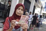 Warga menunjukan uang Bantuan Sosial (Bansos) di Bank Mandiri Kabupaten Ciamis, Jawa Barat, Rabu (19/4/2023). Kementerian sosial membagikan Bansos kepada 10 juta Keluarga Penerima Manfaat (KPM) Program Keluarga Harapan (PKH), 18,8 juta KPM Bantuan Pangan Non Tunai (BPNT), dan 96,8 juta penerima bansos Penerima Bantuan Iuran Jaminan Kesehatan (PBI JK), selama Ramadhan dan jelang Lebaran. ANTARA FOTO/Adeng Bustomi/agr
