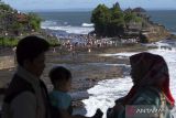Wisatawan menikmati suasana pantai saat berkunjung di objek wisata Tanah Lot, Tabanan, Bali, Minggu (23/4/2023). Pengelola Daya Tarik Wisata (DTW) Tanah Lot mencatat jumlah kunjungan wisatawan saat hari libur Idul Fitri 1444 H pada Sabtu (22/4) sebanyak 9.202 orang, angka tersebut meningkat dibandingkan jumlah kunjungan pada hari-hari biasa yang rata-rata 2.000 orang. ANTARA FOTO/Nyoman Hendra Wibowo/wsj.
