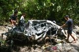 Sejumlah warga mengamati bangkai mobil yang terseret arus banjir bandang di Sembahe, Deli Serdang, Sumatera Utara, Senin (1/5/2023). Berdasarkan data Badan Penanggulangan Bencana Daerah (BPBD) Provinsi Sumatera Utara, banjir bandang yang terjadi pada Minggu 30 April 2023 tersebut mengakibatkan sejumlah fasilitas wisata alam pemandian sungai rusak, dua unit rumah rusak dan satu mobil mini bus terseret arus. ANTARA FOTO/Fransisco Carolio