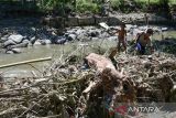 Dua anak berjalan di atas tumpukan material lumpur dan kayu usai banjir bandang di Sembahe, Deli Serdang, Sumatera Utara, Senin (1/5/2023). Berdasarkan data Badan Penanggulangan Bencana Daerah (BPBD) Provinsi Sumatera Utara, banjir bandang yang terjadi pada Minggu 30 April 2023 tersebut mengakibatkan sejumlah fasilitas wisata alam pemandian sungai rusak, dua unit rumah rusak dan satu mobil mini bus terseret arus. ANTARA FOTO/Fransisco Carolio