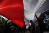 Massa buruh membentangkan bendera Merah Putih saat berunjuk rasa di depan Kantor Gubernur Jawa Timur di Surabaya, Jawa Timur, Senin (1/5/2023). Aksi yang dikuti ribuan buruh dari berbagai serikat pekerja tersebut di antaranya menuntut agar pemerintah mensejahterakan buruh serta merubah ketentuan di UU Cipta Kerja tentang kesejahteraan buruh. Antara Jatim/Moch Asim/zk.