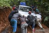 Warga gotong royong mendorong mobil melewati jalan yang terkena tanah longsor di Desa Cisadap, Kabupaten Ciamis, Jawa Barat, Rabu (3/5/2023). BPBD Ciamis menyebutkan sebanyak 14 titik yang tersebar di tujuh kecamatan di Kabupaten Ciamis, dilanda bencana longsor dan banjir akibat curah hujan. ANTARA FOTO/Adeng Bustomi/agr 
