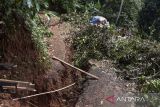 Warga menunjukan kondisi tanah yang retak di Desa Saguling, Kabupaten Ciamis, Jawa Barat, Senin (8/5/2023). Bencana pergerakan tanah seluas dua hektare yang terjadi sejak Jumat (5/5/2023) pagi itu mengakibatkan satu rumah roboh, lima rumah retak dan warga terpaksa mengungsi ditempat yang aman. ANTARA FOTO/Adeng Bustomi/agr
