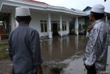 Dua warga menyaksikan bangunan laboratorium yang terkena ledakan semburan lumpur panas yang telah dipagari garis polisi di Pondok Pesantren Nurul Alamiyyah di Wajok Hilir, Kecamatan Jungkat, Kabupaten Mempawah, Kalimantan Barat, Senin (8/5/2023). Semburan lumpur panas tersebut terjadi setelah pihak pondok pesantren melakukan pengeboran tanah sedalam 40 meter untuk mendapatkan sumber air bersih, lalu kemudian terjadi ledakan yang menghantam bangunan laboratorium. ANTARA FOTO/Jessica Helena Wuysang.