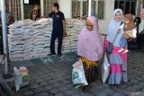 Penyaluran Pangan Beras Tahap Dua. Warga membawa beras usai penyaluran di kantor PT Pos  Indonersia (Persero) Cabang Banda Aceh, Aceh, Jumat (12/5/2023). PT POS Indonesia (Persero ) menargetkan distribusi bantuan pangan beras tahap ke-dua kepada 21,3 juta keluarga penerima manfaat (KPM) di  38 provinsi selesai pada minggu ke dua Mei 2023. ANTARA FOTO/Ampelsa