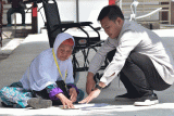 Petugas (kanan) membantu mengeringkan dokumen jamaah calon haji yang basah terkena air di Asrama Haji Embarkasi Bekasi, Jawa Barat, Selasa (23/5/2023). Sebanyak 864 jamaah calon haji serta16 petugas ibadah haji dari Garut dan Cianjur tiba di Asrama Haji Embarkasi Bekasi untuk transit beristirahat sebelum diberangkatkan menuju Tanah Suci. ANTARA FOTO/ Fakhri Hermansyah/rwa.
