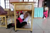 Simulasi penanganan bencana gempa dan tsunami. Pelajar SD Negeri Keumala Bhayangkari berlindung dibawah meja saat mengikuti simulasi penanganan bencana alam gempa dan gelombang tsunami di Banda Aceh, Aceh, Jumat (26/5/2023). Simulasi penanganan bencana gempa dan gelombang tsunami yang digelar Badan Penanggulangan Bencana Daerah (BPBD) Kota Banda Aceh diikuti ratusan pelajar tingkat SD dan SMP yang bertujuan mengedukasi anak-anak sejak usia dini untuk meningkat kesiapsiagaan serta mengurangi resiko saat terjadinya berbagai bencana alam. ANTARA FOTO/Irwansyah Putra.Antara foto/Irwansyah Putra (Antara foto/Irwansyah Putra)