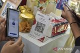 Calon pembeli melakukan pembayaran menggunakan QRIS pada pameran Galuh Digital Fest di Taman Lokasana, Kabupaten Ciamis, Jawa Barat, Sabtu (10/6/2023). Pameran yang diikuti 55 pelaku UMKM dari kuliner, kriya, fesyen dan aplikasi, menerapkan konsep layanan digitalisasi berupa dompet digital, QRIS, dan layanan online. ANTARA FOTO/Adeng Bustomi/agr