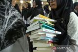 Penjabat Wali Kota Lhokseumawe Imran (kedua kiri) bersama pendidik dan pelajar menunjukkan buku bacaan usai penyerahan bantuan sejuta buku untuk Aceh di SMKN1 Lhokseumawe, Aceh, Rabu (14/6/2023). Bantuan buku yang dicetuskan Yayasan Forum Komunikasi Alumni Lhokseumawe di Jakarta (FoKAL) dan Seuramoe Syedara Lhokseumawe (Seusama) tersebut merupakan program bantuan buku untuk perpustakaan sekolah di 16 kabupaten/kota dalam rangka membantu pemerintah meningkatkan kualitas pendidikan di Aceh. ANTARA/Rahmad