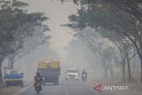 Pengendara sepeda motor melintas di tengah kabut asap akibat kebakaran lahan di Kecamatan Liang Anggang, Banjarbaru, Kalimantan Selatan, Jumat (23/6/2023). Berdasarkan tabel kualitas udara Badan Meteorologi, Klimatologi dan Geofisika (BMKG) pada Jumat (23/6) kualitas udara di Banjarbaru mengalami kenaikan dari baik ke sedang hal ini di akibatkan salah satunya dampak kabut asap dari kebakaran hutan dan lahan (Karhutla) yang mulai meluas di Kalsel. ANTARA/Bayu Pratama S.