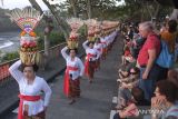 Wisatawan menyaksikan ratusan perempuan Bali menjunjung gebogan atau sesajen berisi buah, kue, bunga dan hiasan janur saat parade mapeed pada Tanah Lot Art and Food Festival IV di objek wisata Tanah Lot, Tabanan, Bali, Sabtu (24/6/2023). Kegiatan tersebut digelar sebagai daya tarik wisata guna meningkatkan jumlah kunjungan wisatawan di objek wisata itu yang saat ini jumlahnya rata-rata 8.000 orang per hari. ANTARA FOTO/Nyoman Hendra Wibowo/wsj.