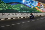 Kendaraan melintas di samping dinding jalan dengan coretan vandalisme di Underpass Dewi Sartika, Depok, Jawa Barat, Selasa (27/6/2023). Aksi vandalisme yang dilakukan oleh oknum yang tidak bertanggung jawab tersebut dapat merusak keindahan jalan underpass Dewi Sartika yang telah diresmikan pada Januari 2023 lalu. ANTARA FOTO/Asprilla Dwi Adha/nym.