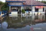 Warga melewati genangan banjir rob yang merendam halaman Mako Satpolair Polres Indramayu di Karangsong, Indramayu, Jawa Barat, Selasa (11/7/2023). Banjir rob yang disebabkan pasang air laut merendam jalan dan puluhan rumah warga yang berada di pesisir pantai. ANTARA FOTO/Dedhez Anggara/agr