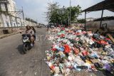 Warga melintas di samping sampah yang meluber ke jalan di Tempat Pembuangan Sampah Sementara (TPSS), Pancoran Mas, Depok, Jawa Barat, Rabu (12/7/2023). Sampah yang telah melebihi kapasitas hingga meluber ke satu lajur jalan itu imbas dari terlambatnya truk pembuangan sampah yang juga terhambat dalam pembuangan sampah di TPA Cipayung. ANTARA FOTO/Asprilla Dwi Adha/foc.