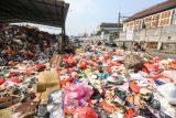 Warga melintas di samping sampah yang meluber ke jalan di Tempat Pembuangan Sampah Sementara (TPSS), Pancoran Mas, Depok, Jawa Barat, Rabu (12/7/2023). Sampah yang telah melebihi kapasitas hingga meluber ke satu lajur jalan itu imbas dari terlambatnya truk pembuangan sampah yang juga terhambat dalam pembuangan sampah di TPA Cipayung. ANTARA FOTO/Asprilla Dwi Adha/foc.