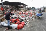 Warga melintas di samping sampah yang meluber ke jalan di Tempat Pembuangan Sampah Sementara (TPSS), Pancoran Mas, Depok, Jawa Barat, Rabu (12/7/2023). Sampah yang telah melebihi kapasitas hingga meluber ke satu lajur jalan itu imbas dari terlambatnya truk pembuangan sampah yang juga terhambat dalam pembuangan sampah di TPA Cipayung. ANTARA FOTO/Asprilla Dwi Adha/foc.