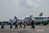 Penumpang berjalan menuju pesawat di Bandara Husein Sastranegara, Bandung, Jawa Barat, Kamis (13/7/2023). Presiden Joko Widodo menyatakan, penerbangan dari Bandara Husein Sastranegara akan beralih ke Bandara Internasional Kertajati mulai Oktober 2023 seiring dengan rampungnya infrastruktur penunjang yaitu Jalan Tol Cisumdawu. ANTARA FOTO/Raisan Al Farisi/agr