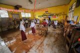 Pelajar dan guru membersihkan kelas yang terendam banjir di SDN 98 Kota Jambi, Jambi, Selasa (18/7/2023). Banjir yang terjadi akibat meluapnya anak sungai di belakang sekolah setelah kota itu dilanda hujan deras selama 3 jam lebih mengakibatkan hampir semua ruangan kelas terendam, dan selama tahun ini sekolah tersebut telah terdampak banjir hingga sepuluh kali. ANTARA FOTO/Wahdi Septiawan/aww.