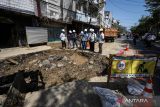 Pekerja memperbaiki jalan di lokasi aspal yang terangkat di Jalan Pasar Kembang, Surabaya, Jawa Timur, Selasa (1/8/2022). Kerusakan jalan yang sempat membuat panik warga sekitar lokasi itu diakibatkan proyek peremajaan pipa air PDAM Surya Sembada Surabaya. ANTARA Jatim/Rizal Hanafi/zk